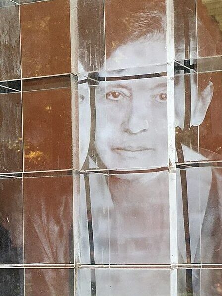 Glasinstallation mit dem Porträt der Physikerin Lise Meitner im Arkadenhof der Universität Wien, vor historischer Architektur.