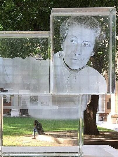 Glasdenkmal mit dem Porträt der Physikerin Berta Karlik auf einem Sockel im Innenhof der Universität Wien.