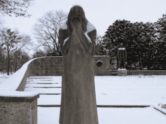Allegorische Darstellung im Vollbild einer trauernden Frau, die sich die Hände ins Gesicht hält am verschneiten Mahnmal gegen Faschismus am Zentralfriedhof.