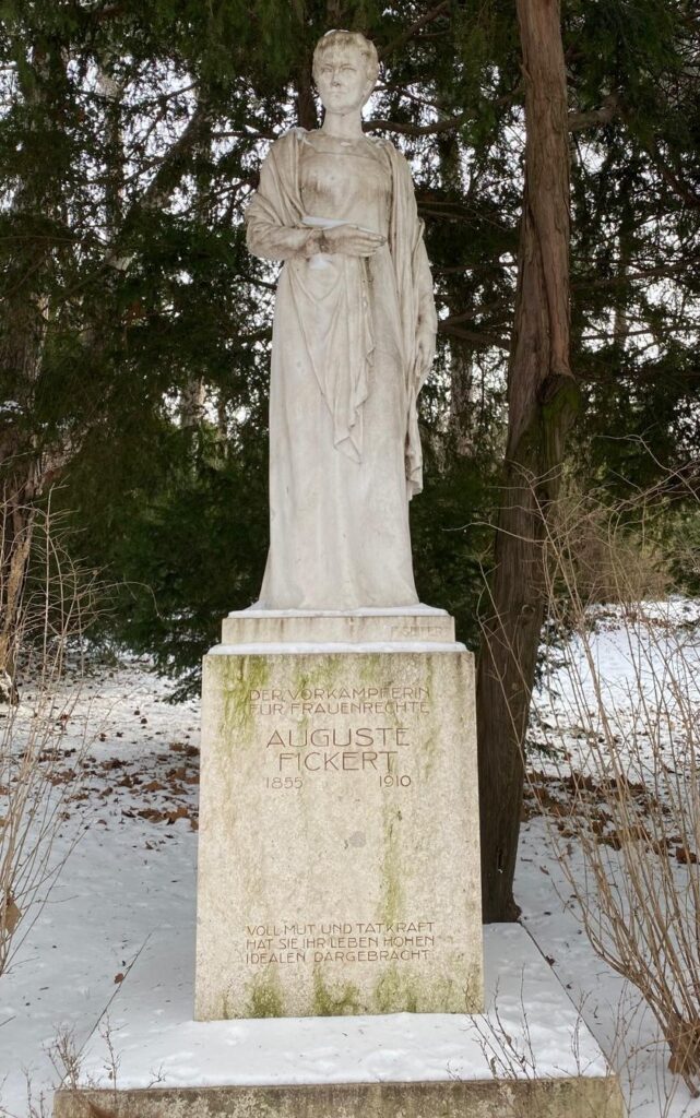 Denkmal der Sozialreformerin Auguste Fickert im Türkenschanzpark zeigt sie stehend auf einem Steinblock, die rechte Hand zum Bauch geführt. 