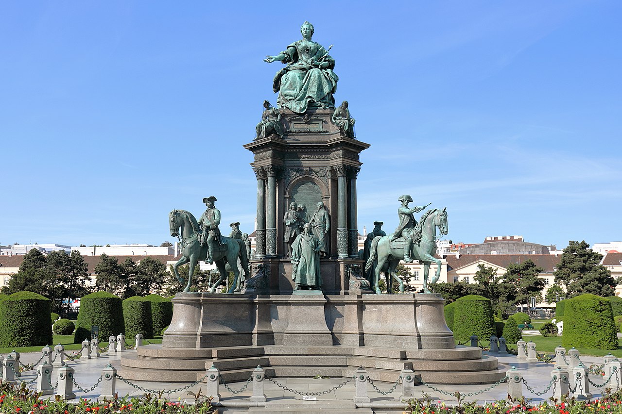 Monumentales Maria-Theresia-Denkmal am Maria-Theresien-Platz in Wien mit der sitzenden Kaiserin im Zentrum, umgeben von mehreren männlichen Figuren aus Politik, Militär, Wissenschaft und Kunst.